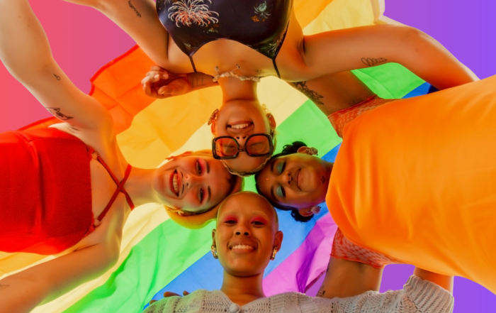 Trans and nonbinary teens encircling one another, expressing joy and fulfillment, because of their supportive families and communities